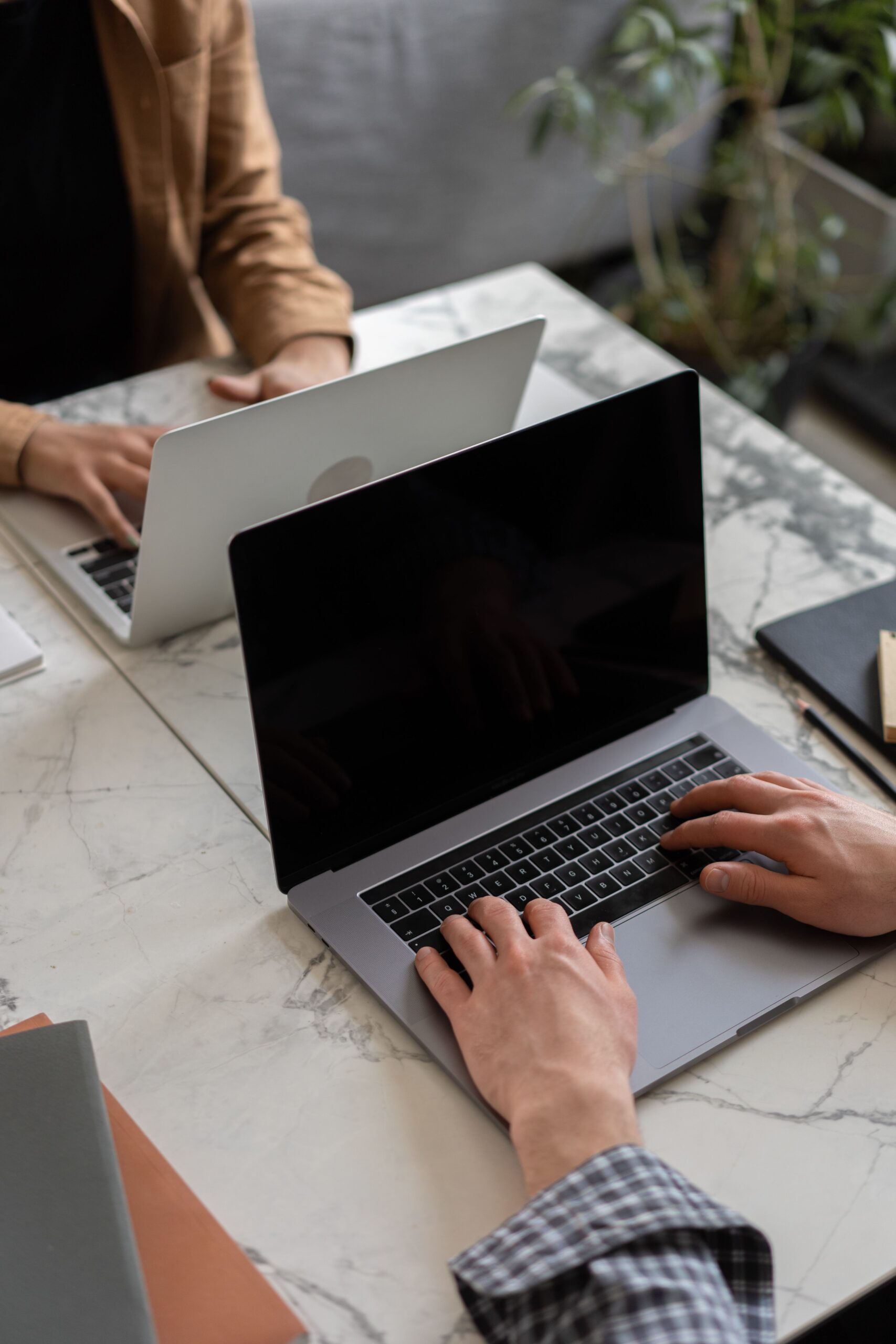 Two people working on laptops in a modern office setting, showcasing teamwork and productivity.
