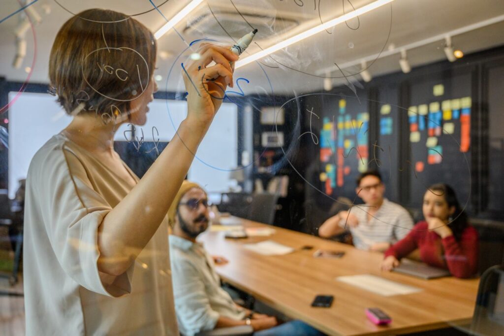 Team members brainstorm with ideas on a clear board in a modern office setting.